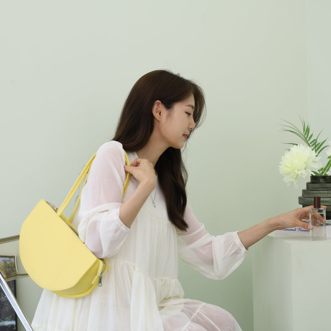 sac jaune lemon couleur sur l'épaule d'une fille en robe blache