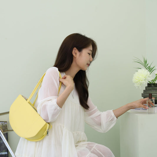 sac jaune lemon couleur sur l'épaule d'une fille en robe blache